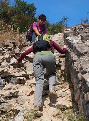 Guide helping a traveler on a steep Great Wall trail