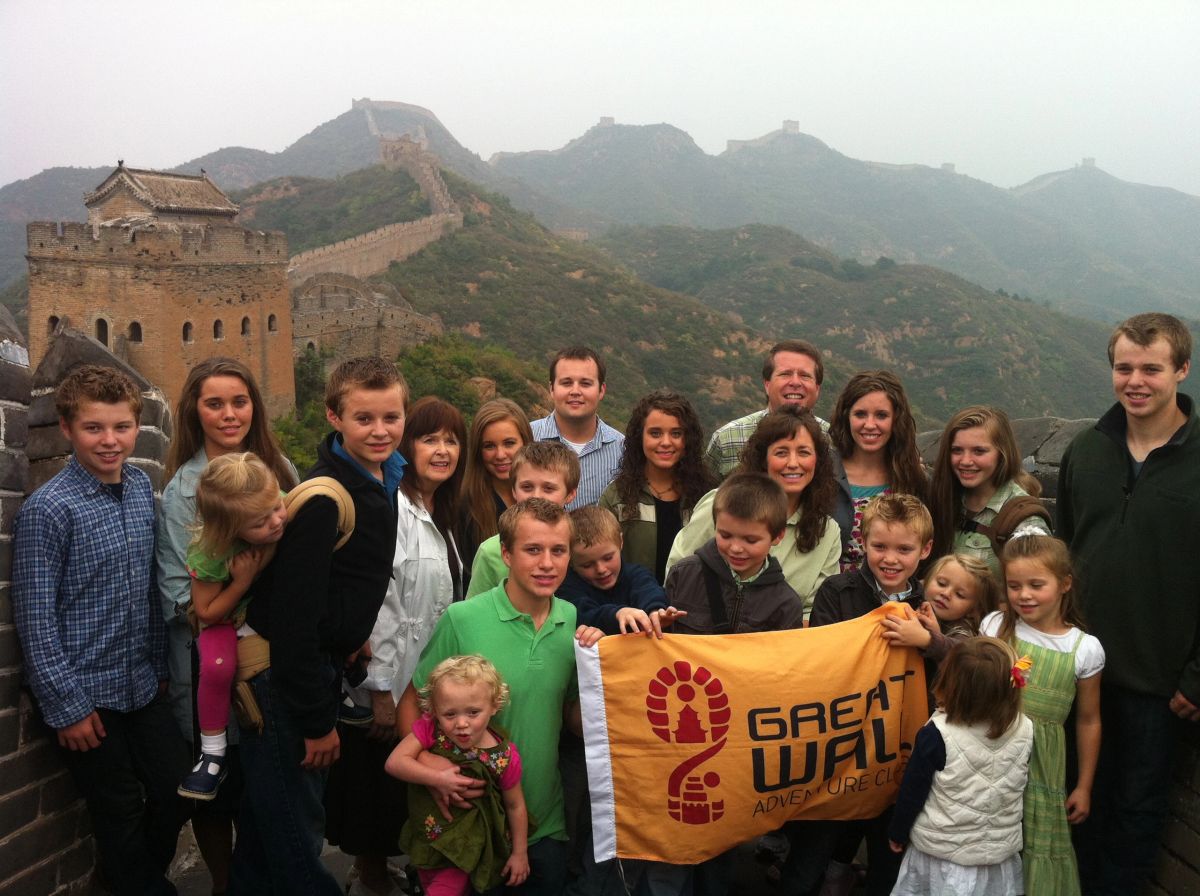 The Duggar family on the Great Wall with a Great Wall Adventure Club banner